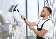 man outside cleaning commercial window